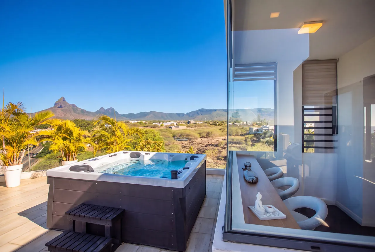 Jacuzzi sur terrasse, offrant une vue dégagée sur la montagne. Ambiance paisible et spacieuse.