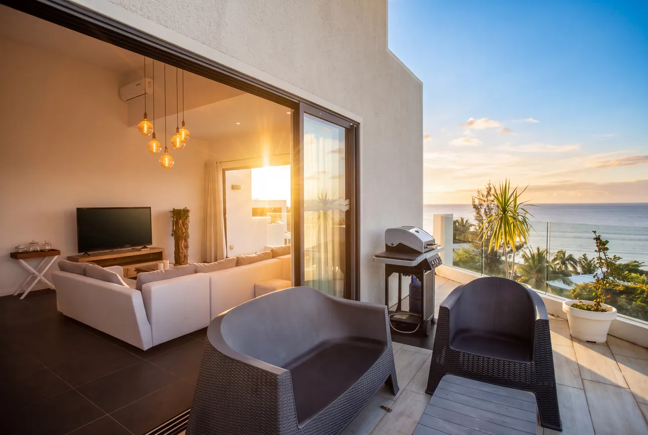 Terrasse en bois avec mobilier de jardin et vue sur la mer. Éclairage naturel avec une ambiance chaleureuse.