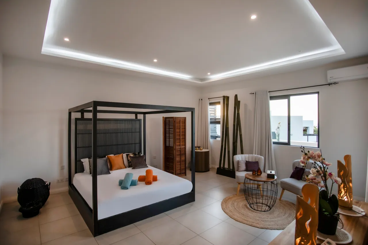 Chambre principale avec lit à baldaquin et éclairage doux. Vue sur l'extérieur depuis la fenêtre.