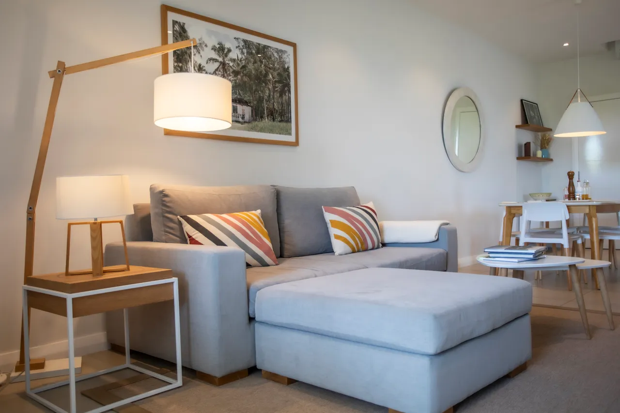 Salon avec canapé en L et lampe sur pied, décoré de coussins colorés.