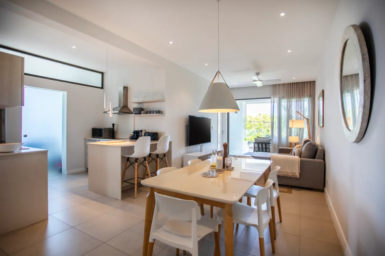 Espace repas lumineux avec table blanche et chaises en plastique.