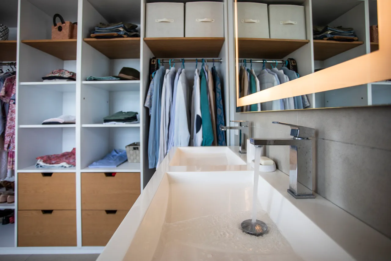 Salle de bain spacieuse avec double vasque et rangement intégré. Miroir lumineux accentue l’espace.