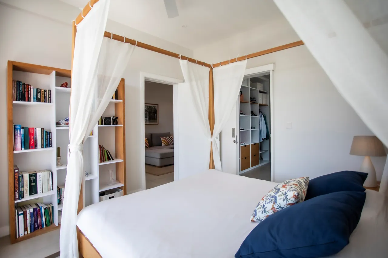 Tons neutres et textiles légers créent une ambiance apaisante. Lit double avec rangement intégré et étagères personnalisées.