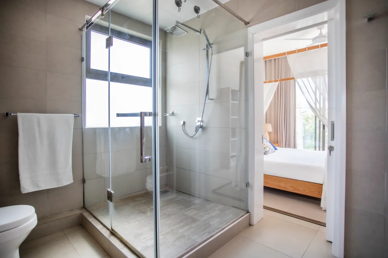 Salle de bain dotée d'une douche à l'italienne et carrelage clair.