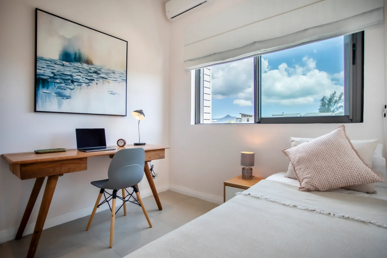 Espace de travail fonctionnel avec bureau en bois et chaise design. Fenêtre laissant entrer la lumière naturelle.