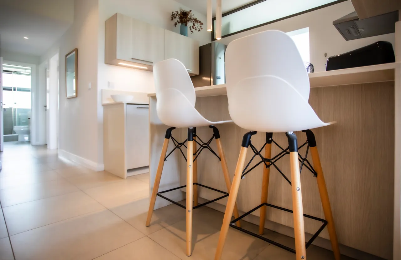 Cuisine complète avec bar et chaises hautes. Éléments pratiques pour préparer des repas.