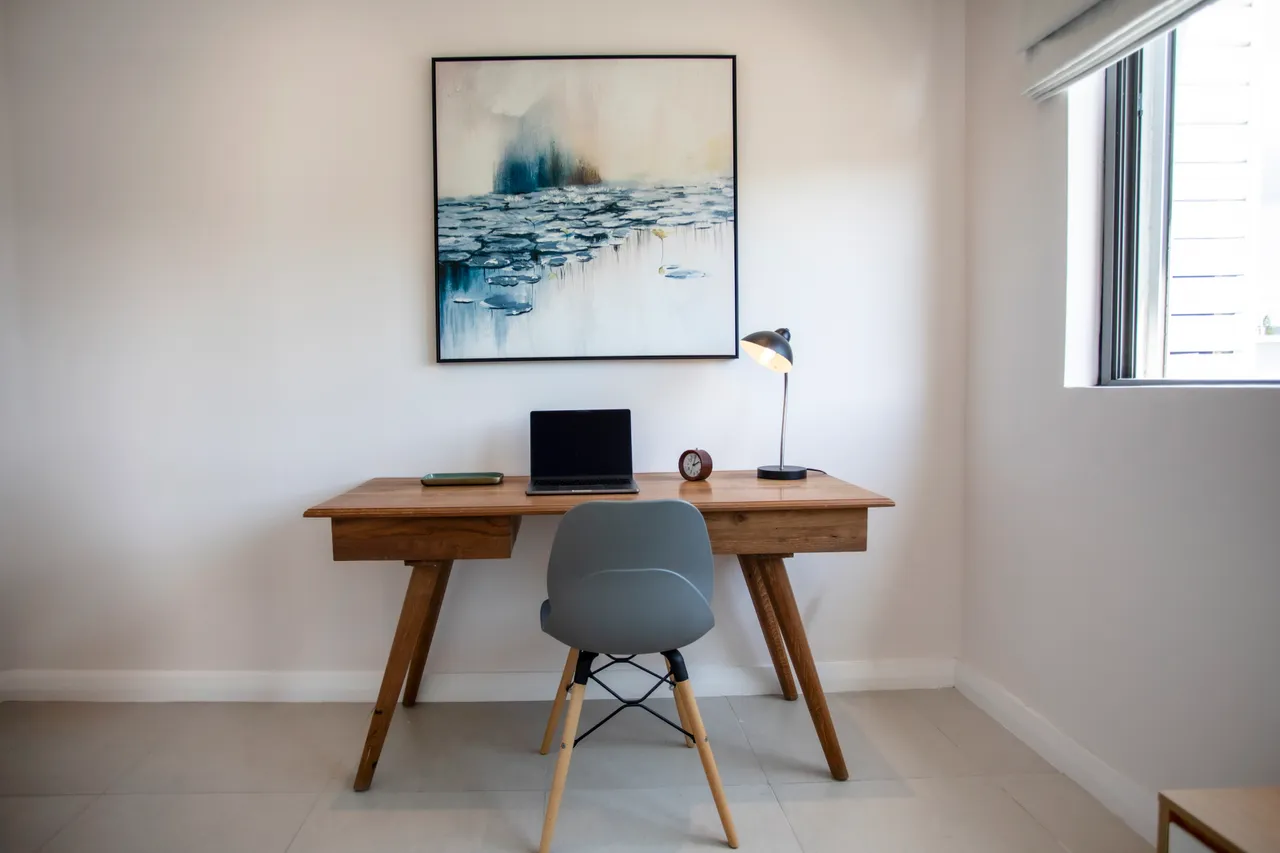 Bois clair et lignes épurées caractérisent cet espace de travail. Bureau fonctionnel avec chaise design et fenêtre lumineuse.