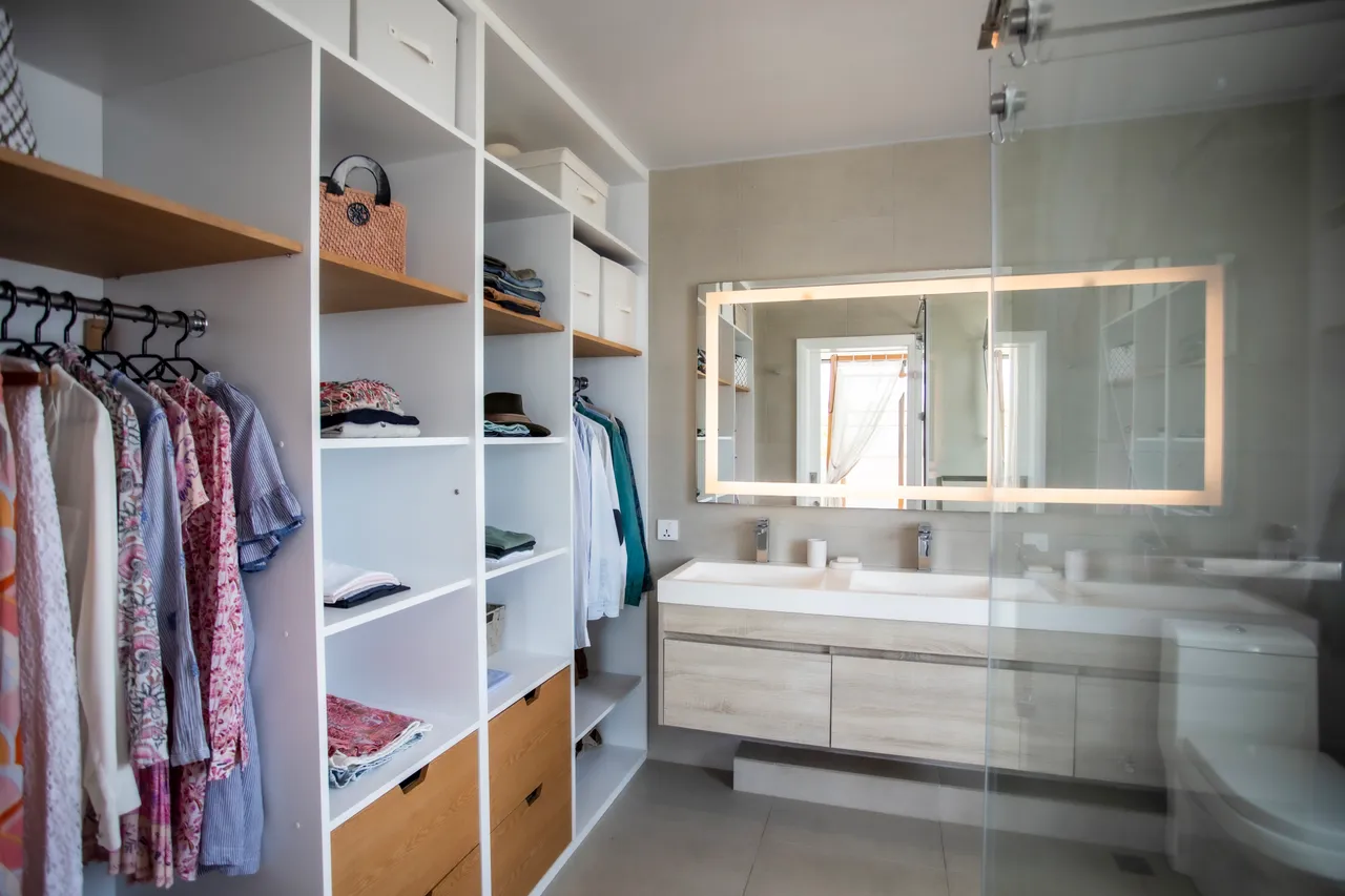 Salle de bain spacieuse avec double vasque et rangement intégré. Douche à l'italienne et éclairage doux. Mur carrelé et fenêtre offrant lumière naturelle.