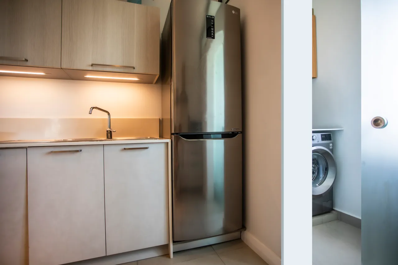Buanderie avec lave-linge et espace de rangement fonctionnel. Éclairage intégré pour une utilisation pratique.