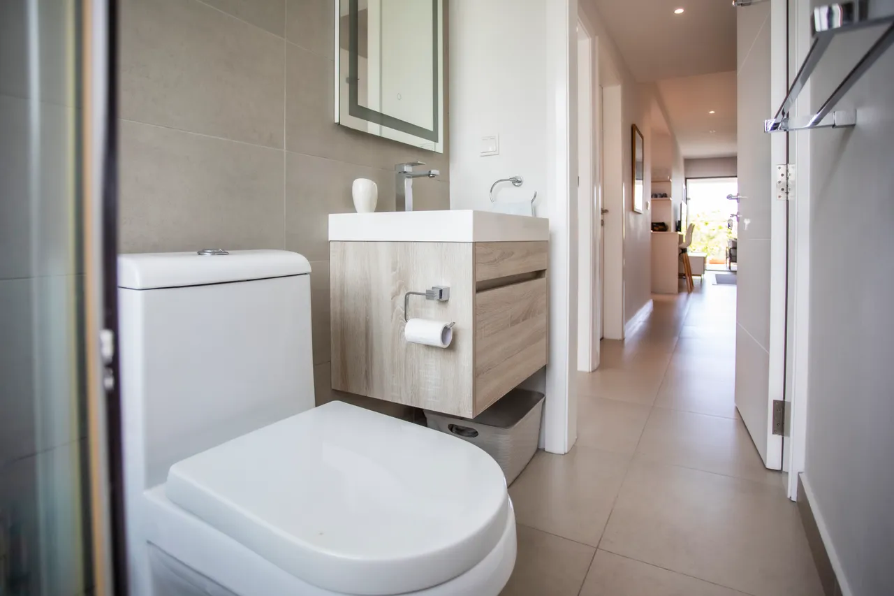 Salle de bain moderne avec meuble sous-vasque en bois et miroir. Espace épuré bénéficiant d'une bonne luminosité.