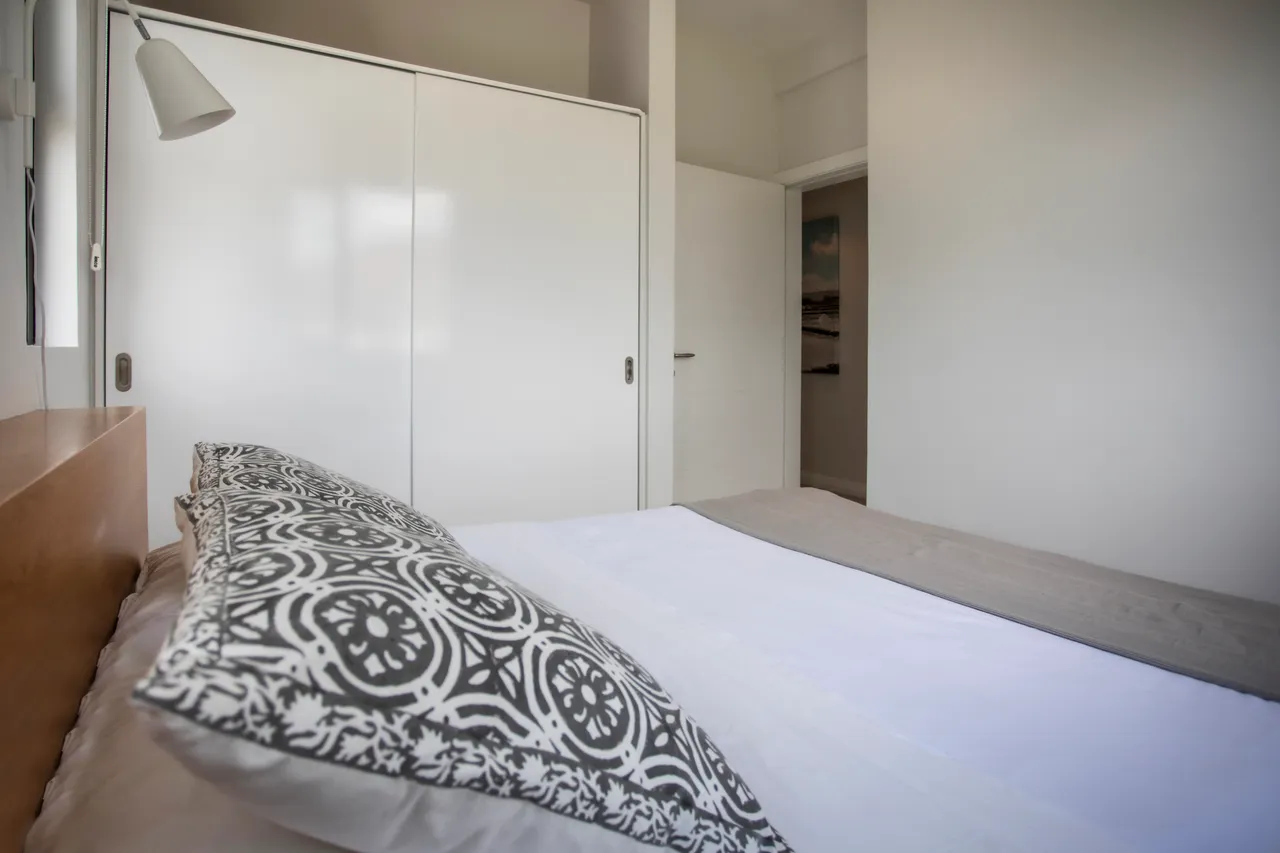 Chambre avec lit double et rangement intégré. Décoration sobre et éclairage naturel.
