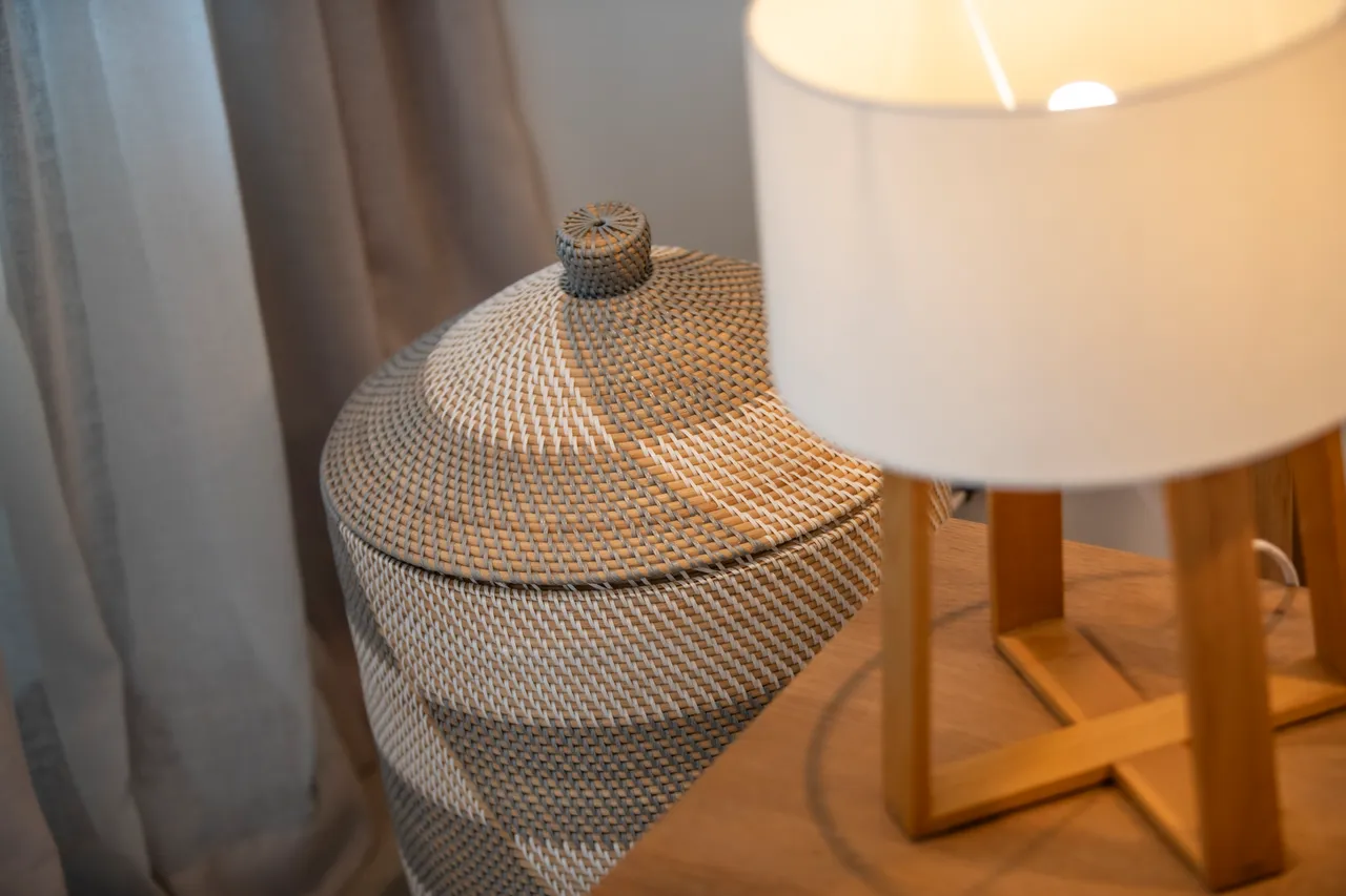 Détails décoratifs avec lampe moderne et panier tressé en fibres naturelles. Éléments de rangement pratiques et design simple.