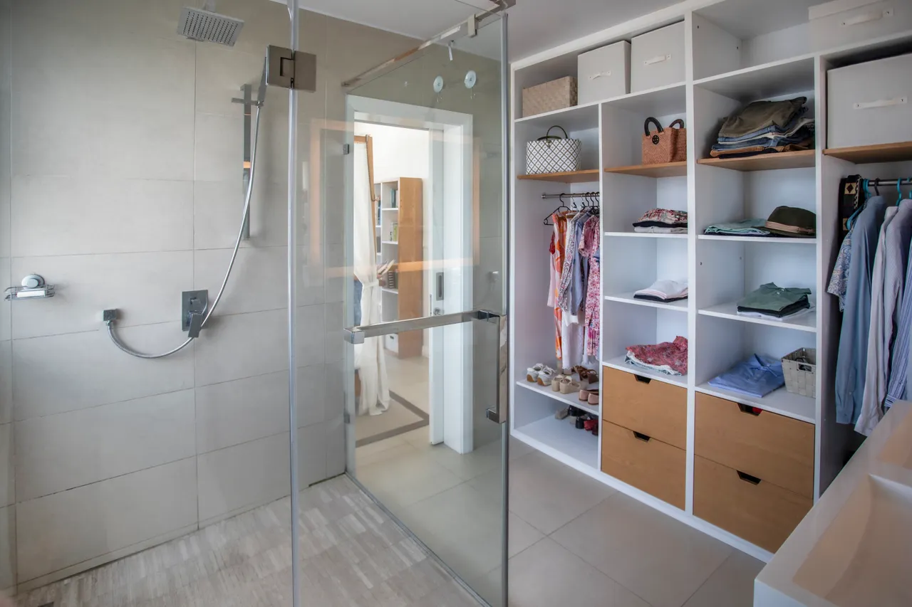 Salle de bain avec douche à l'italienne et rangement ouvert. Éclairage naturel et décoration épurée.