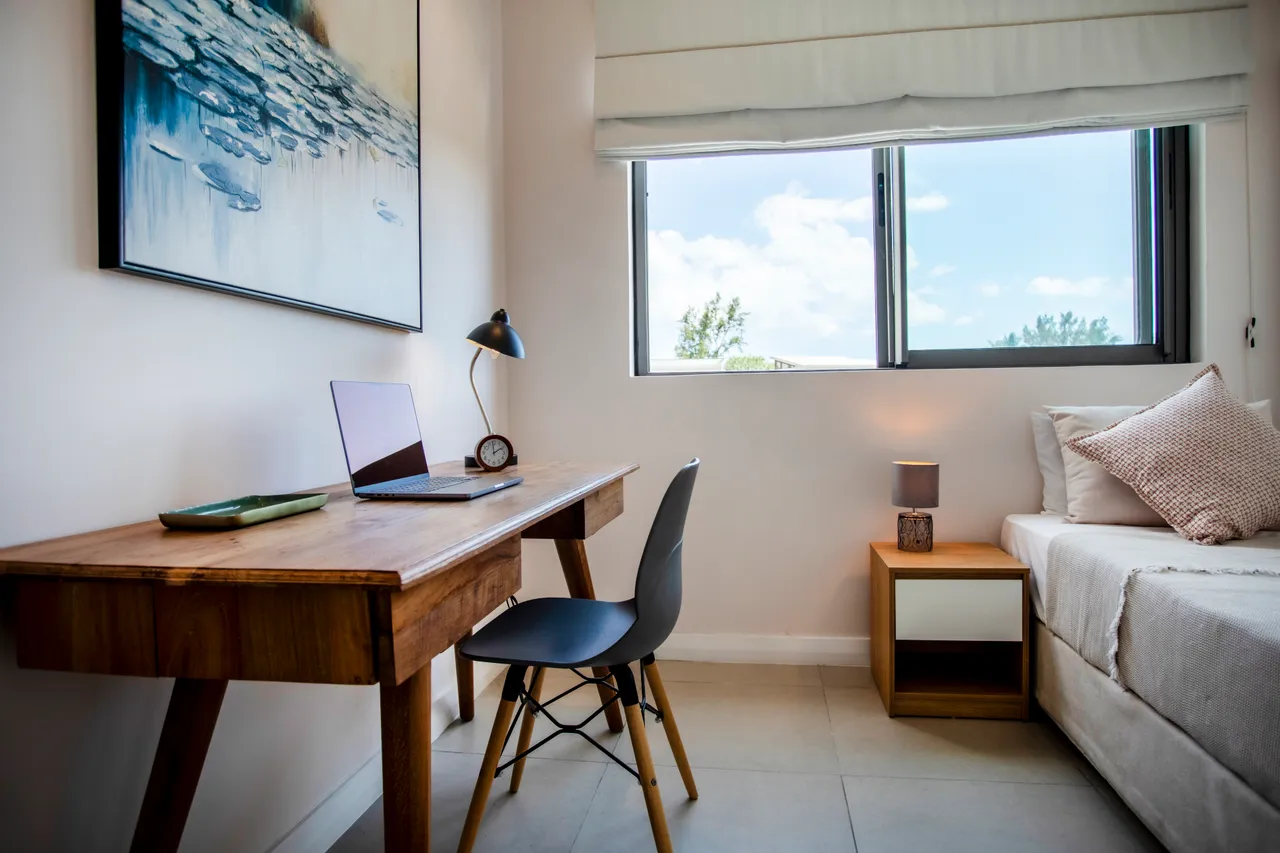 Espace de travail équipé d'un bureau en bois et d'une chaise. Fenêtre offrant une lumière naturelle.