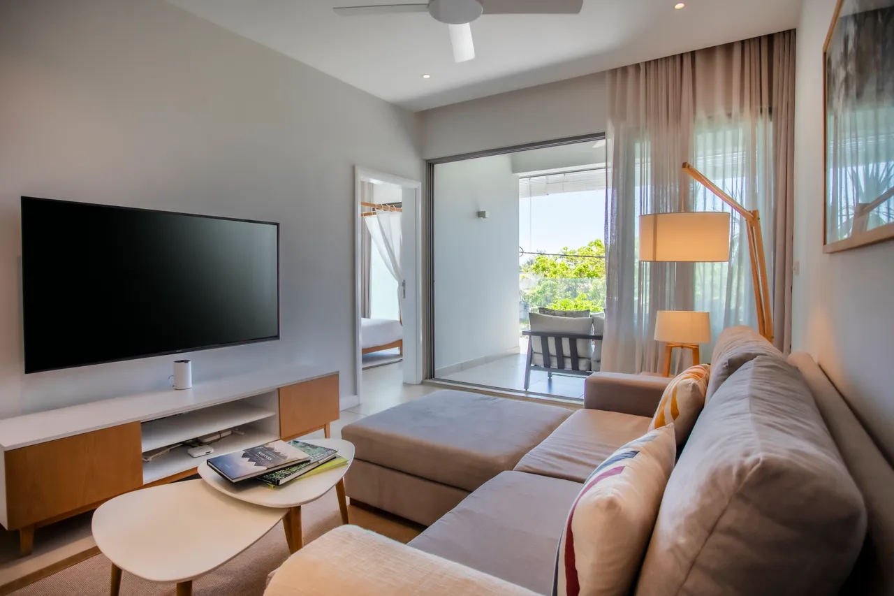Espace lumineux avec canapé modulable et télévision murale. Accès direct au balcon depuis le salon.
