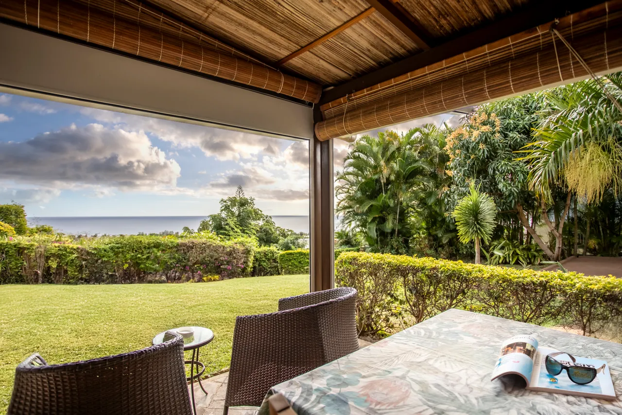 Terrasse couverte avec vue dégagée sur l'océan et le jardin. 

Mobilier en osier offrant un espace confortable pour se détendre. 

Grandes ouvertures permettant une belle luminosité naturelle. 

Espace extérieur bien entretenu avec verdure et fleurs.