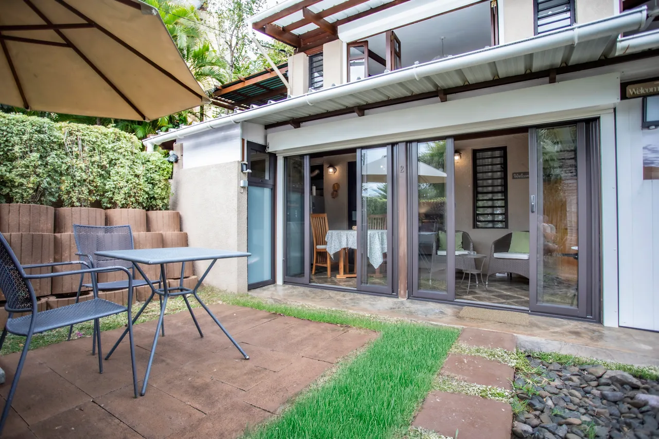 Espace extérieur avec chaises et table sur une terrasse en dalles.
