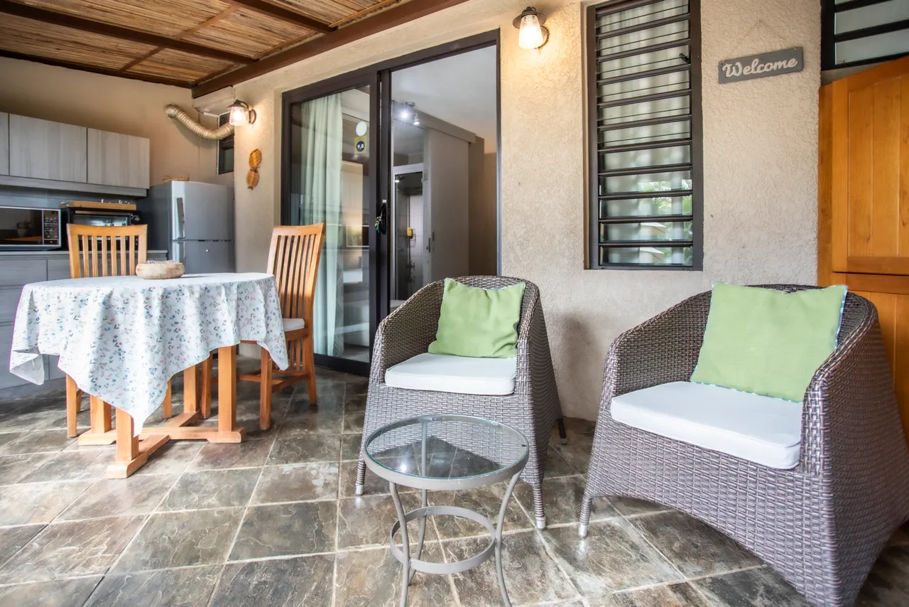 Terrasse en carrelage avec mobilier en rotin et table à manger.