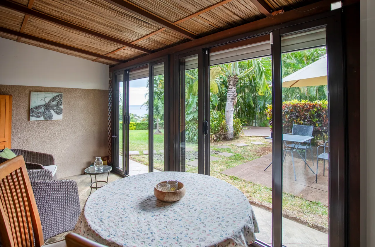 Galerie avec vue sur le jardin, équipée d'une table et chaises.