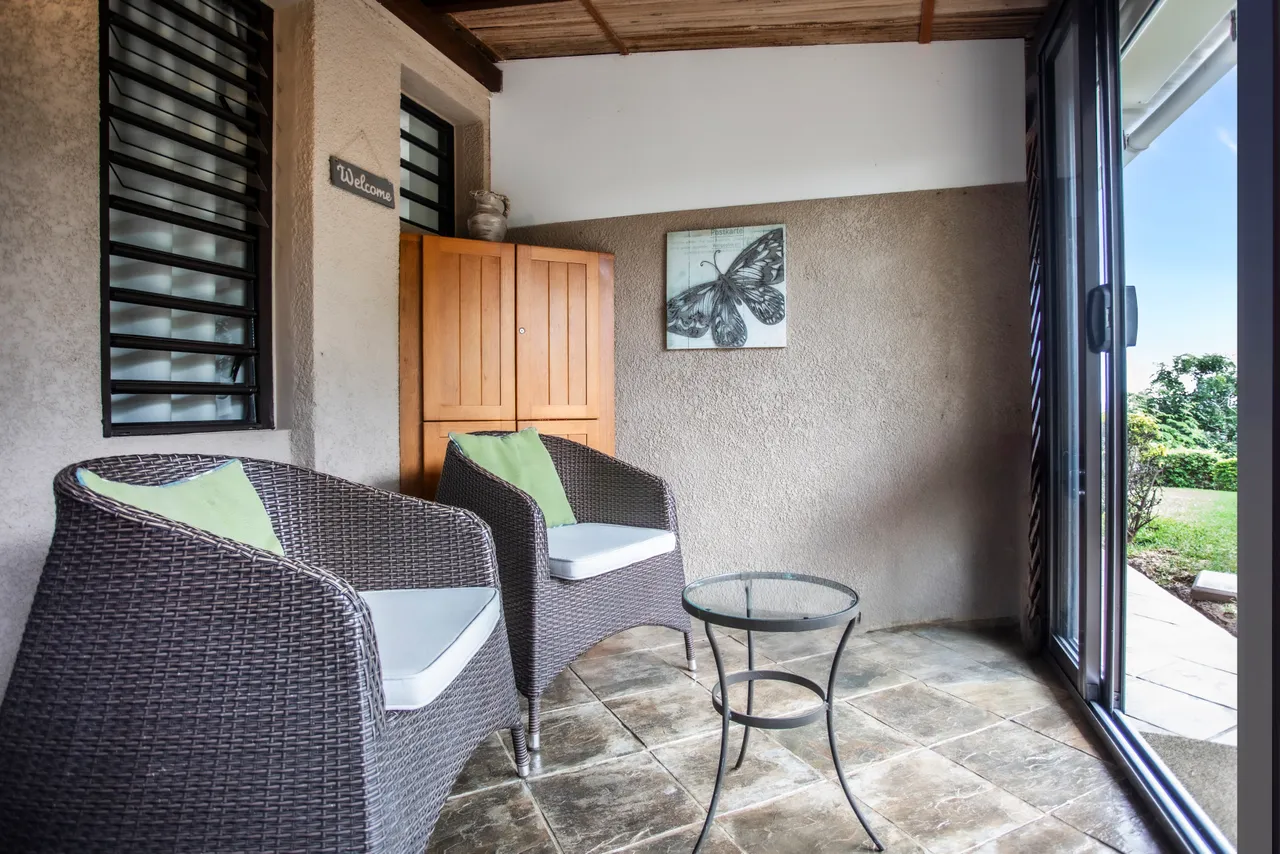 Espace de galerie avec fauteuils en rotin et table basse en verre.