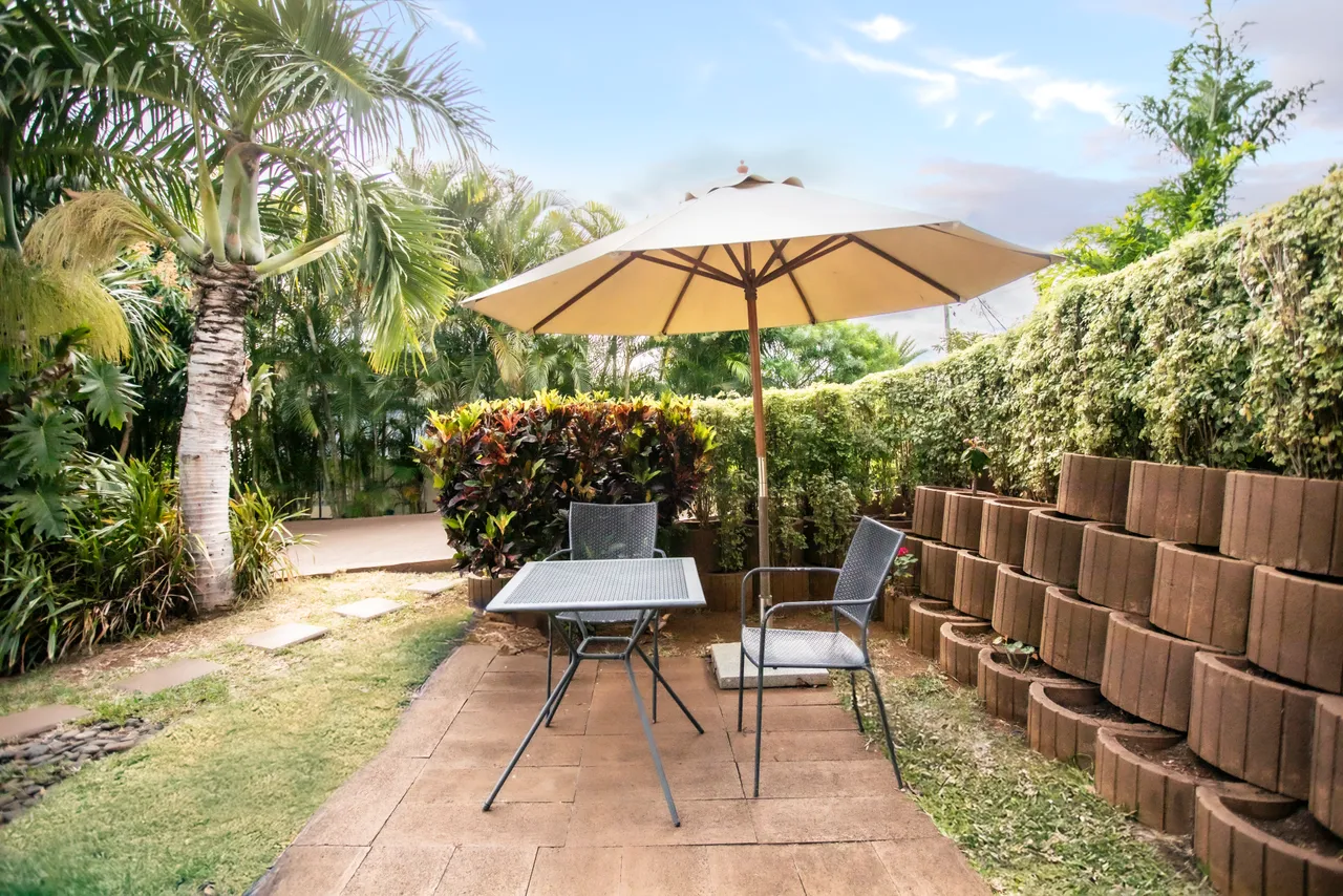Terrasse en pavés avec une table et des chaises sous un parasol.