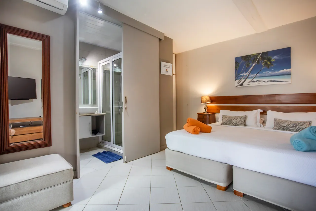 Chambre dotée d'un lit double et d'un décor épuré. Accès à une salle de bain attenante avec douche vitrée.