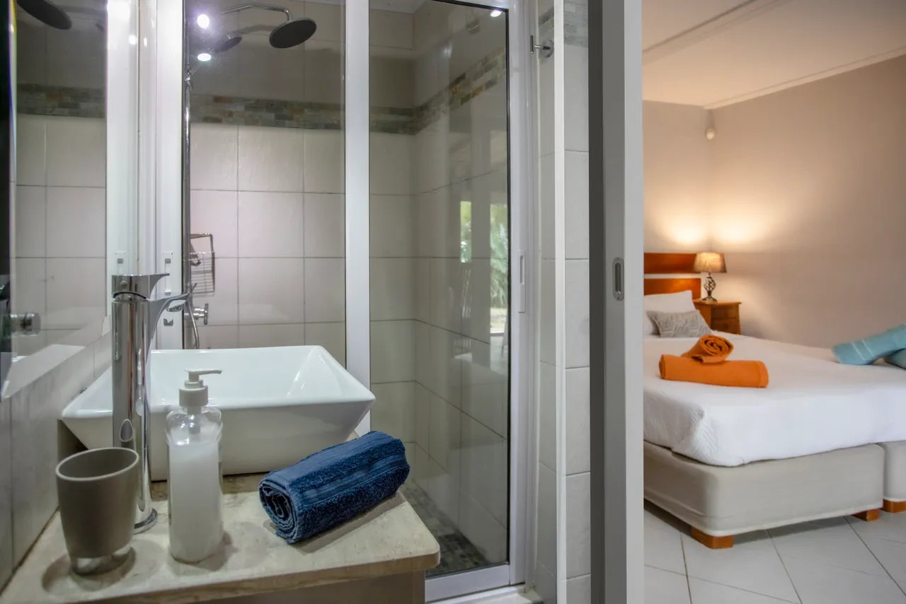 Salle de bain moderne avec douche vitrée et vasque sur meuble. Serviettes disposées avec soin.