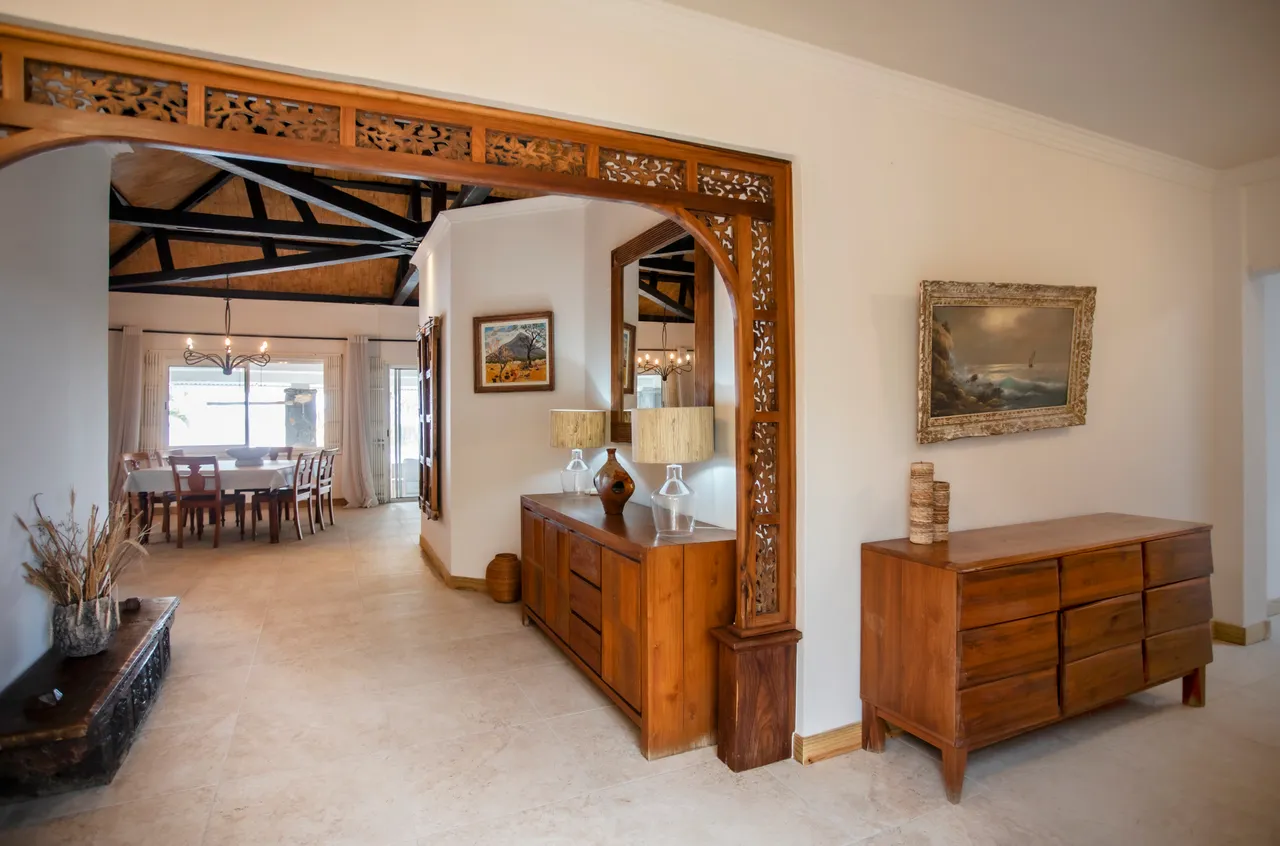 Entrée spacieuse avec meubles en bois et éclairage chaleureux. Accès au salon et à la salle à manger.