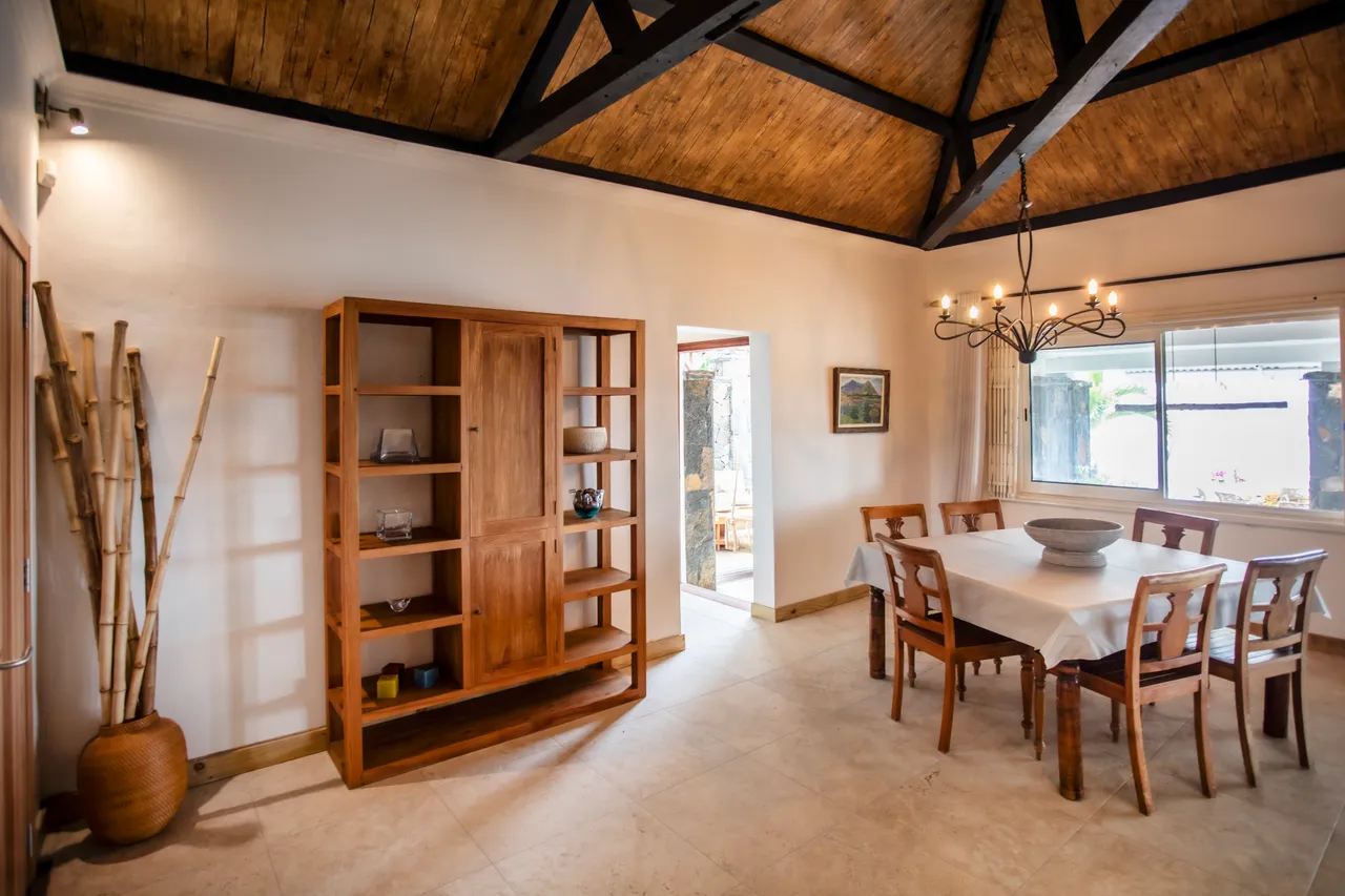 Espace repas avec table en bois et chaises assorties. Éclairage naturel à travers les fenêtres.