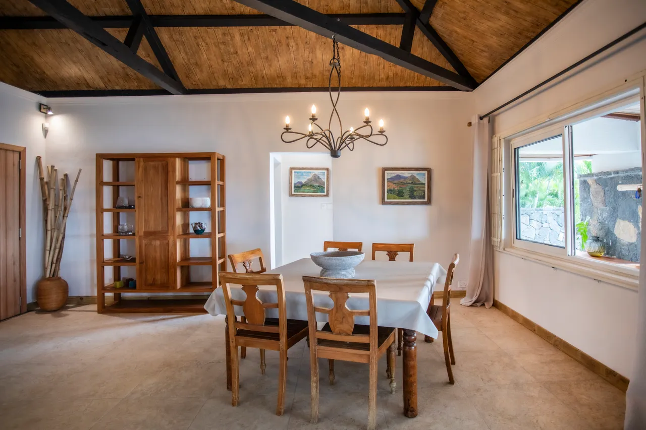 Espace repas avec table en bois et chaises en bois. Plafond voûté en matériaux naturels.