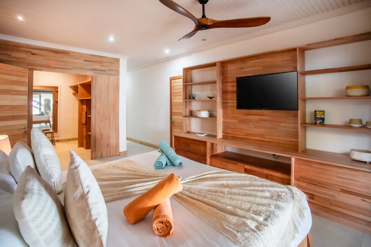 Chambre équipée d'un lit double et d'un téléviseur mural. Rangements intégrés et coin dressing accessible. Éclairage doux avec lampes de chevet.