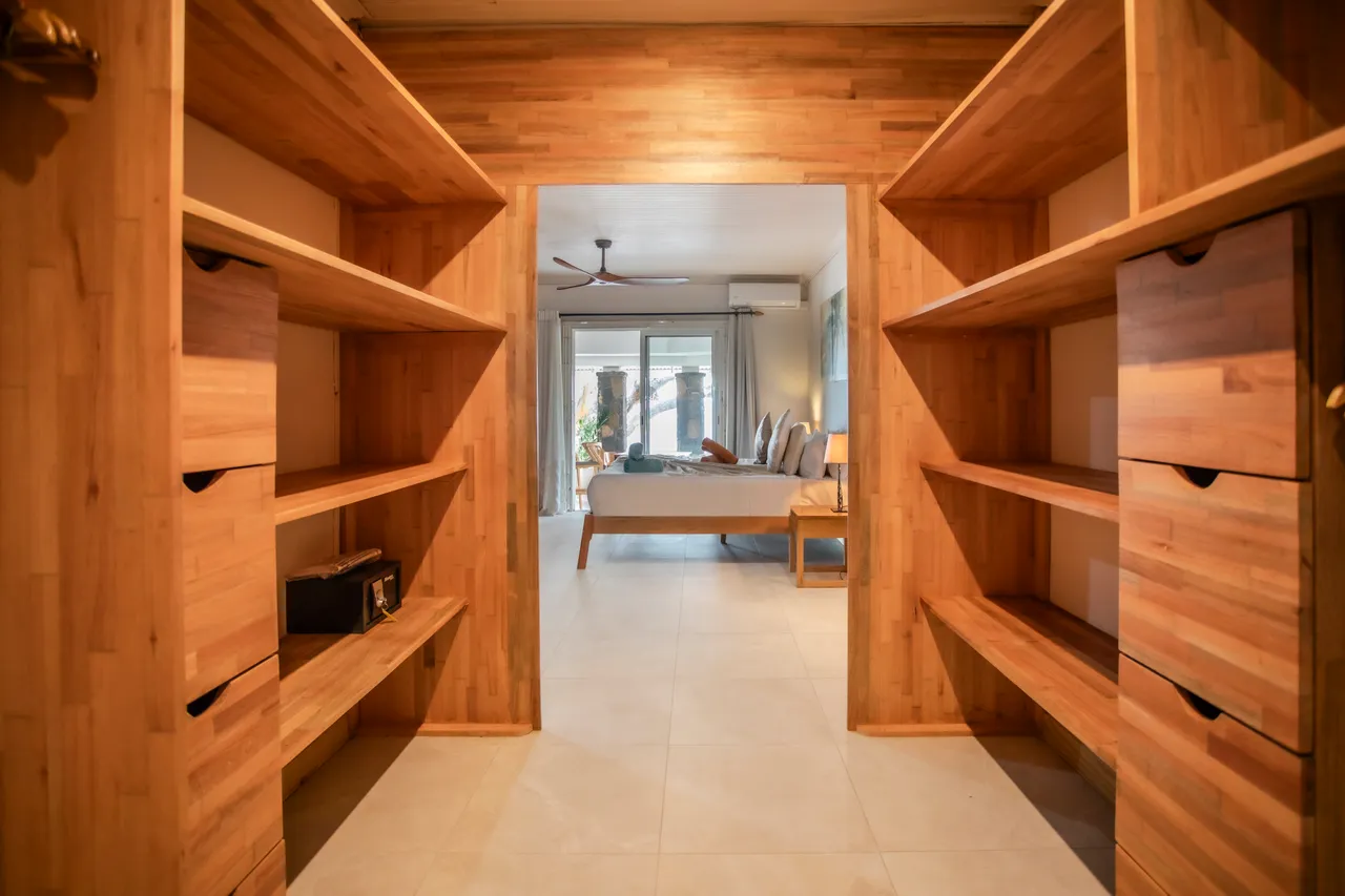 Bois clair des étagères intégrées pour un rangement pratique. Accès direct à la chambre. Éclairage naturel provenant de la pièce voisine.