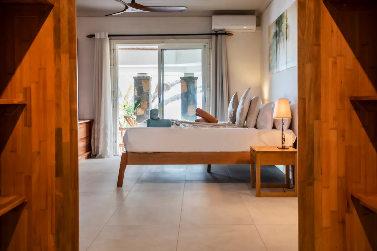 Chambre avec lit en bois et draps clairs, accès direct à la terrasse.