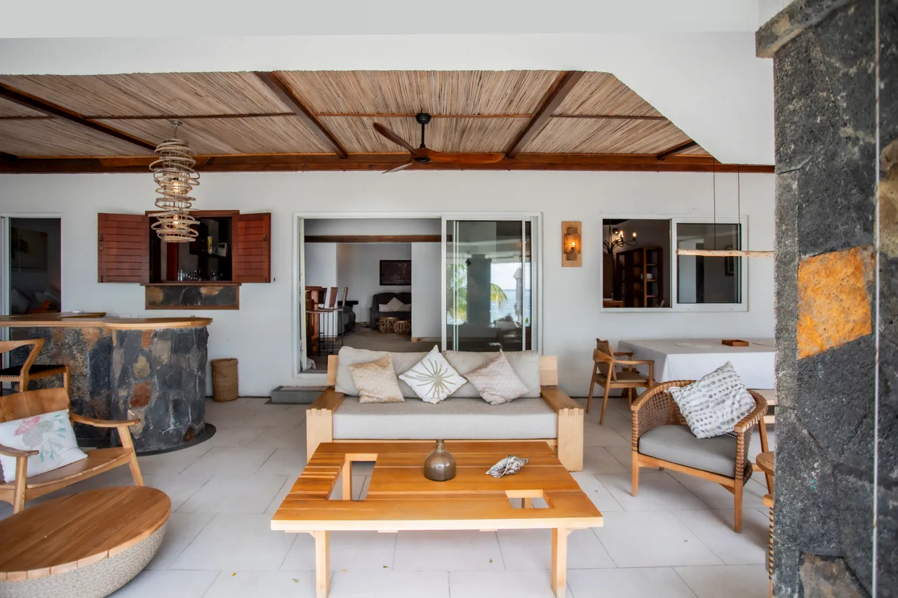 Terrasse couverte avec mobilier en bois et vue sur la mer. Espace propice à la détente.