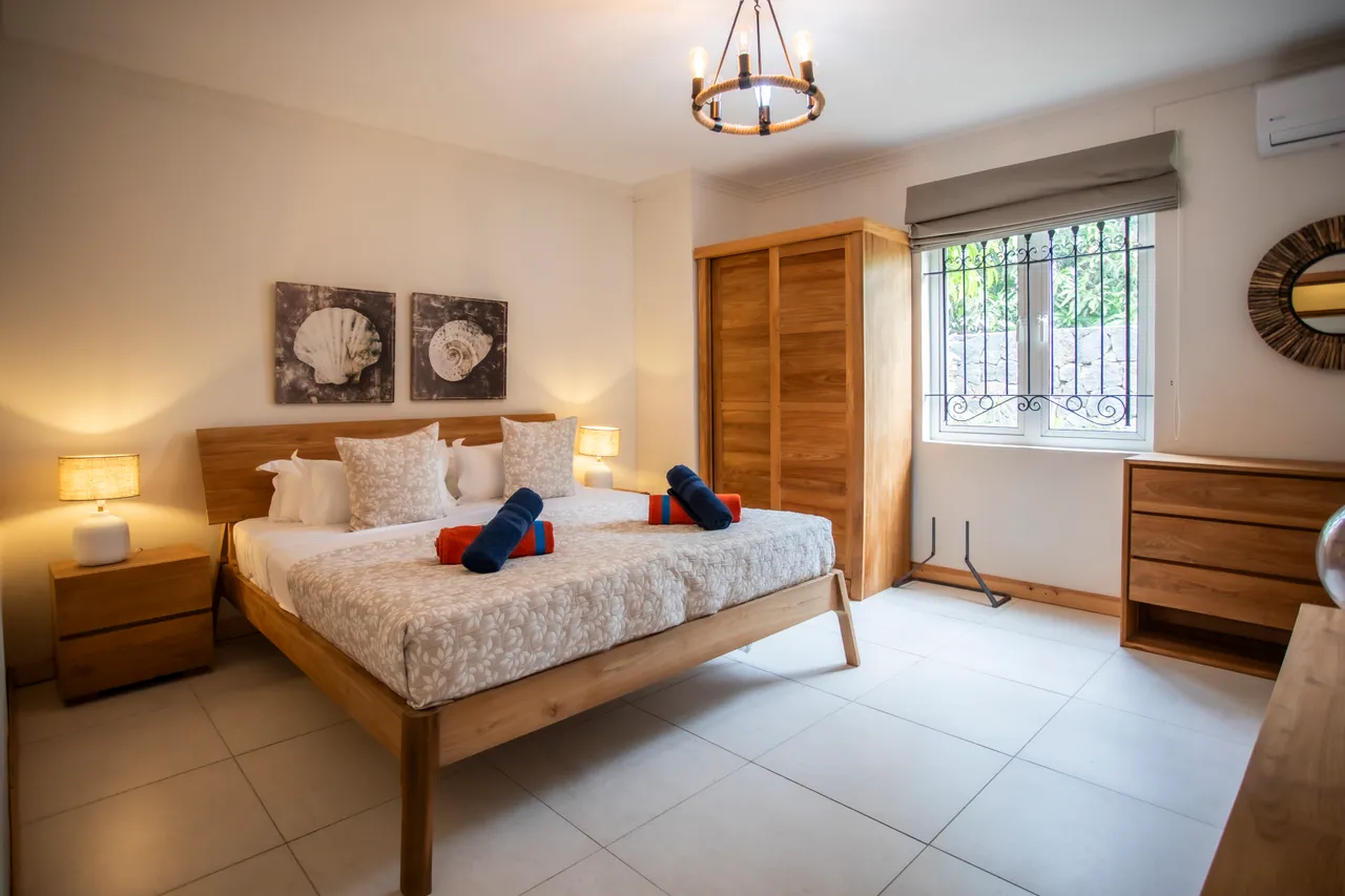 Chambre avec lit en bois et décor apaisant. Rangement intégré et éclairage chaleureux. Éléments décoratifs en harmonie avec l'espace.