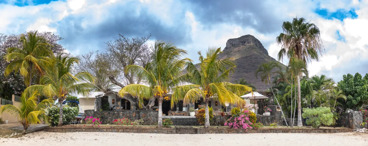 Végétation tropicale encadrant la villa en bord de mer. Accès direct à la plage de sable blanc.