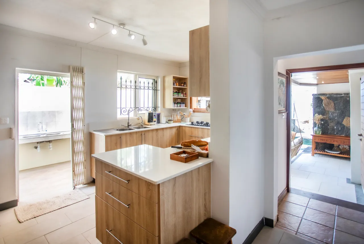 Cuisine moderne avec plans de travail en bois et appareils intégrés. Accès à un espace extérieur.