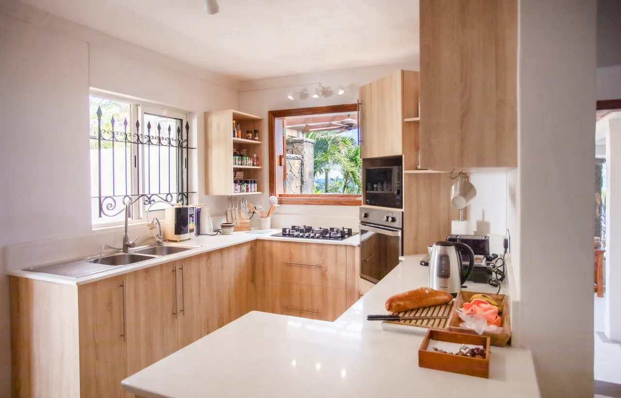 Cuisine fonctionnelle avec meubles en bois et équipements modernes. Lumière naturelle et vue sur l'extérieur.