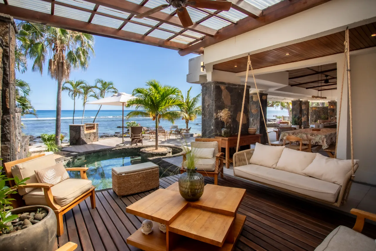 Lumière naturelle abondante avec terrasse donnant sur la piscine et la mer. Mobilier en bois pour un espace de vie confortable.