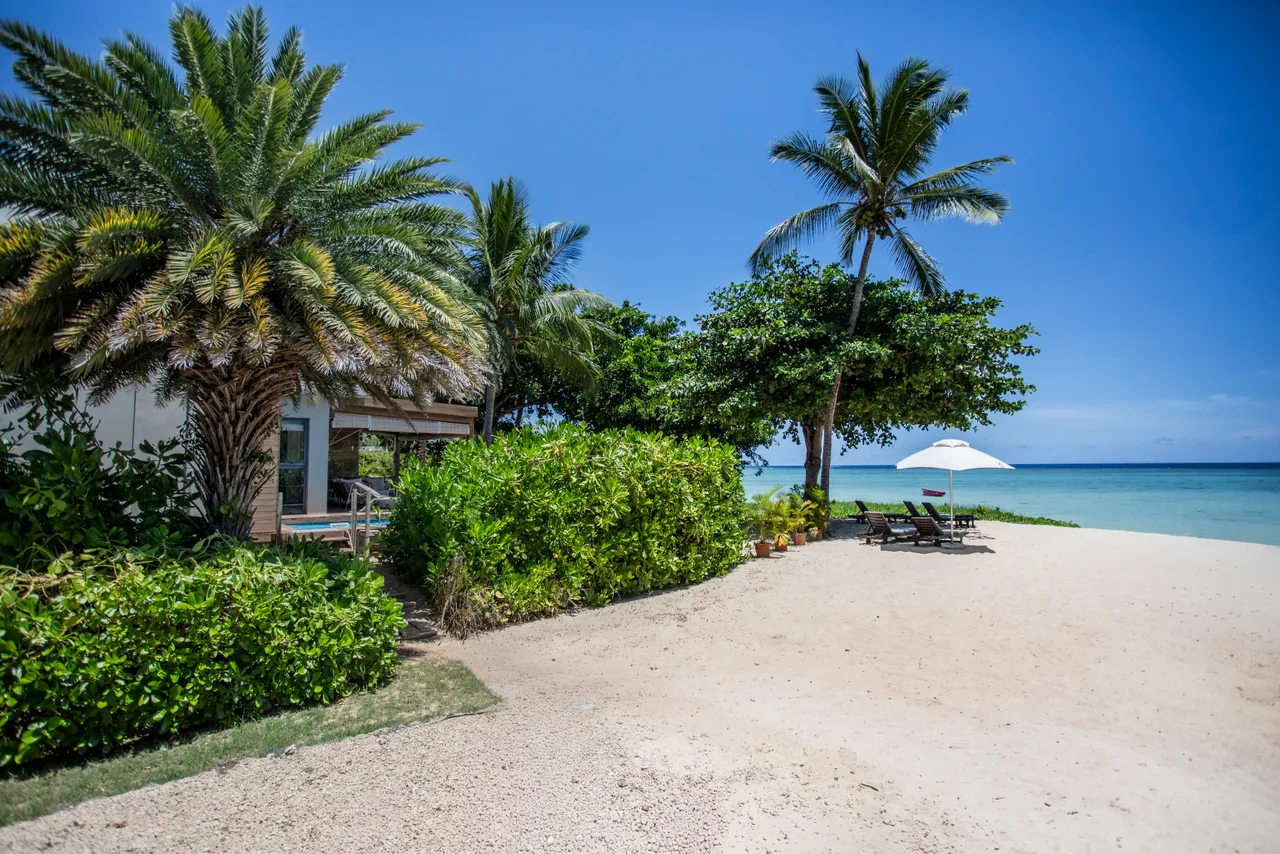 Accès direct à la plage depuis le jardin, avec des chaises longues.