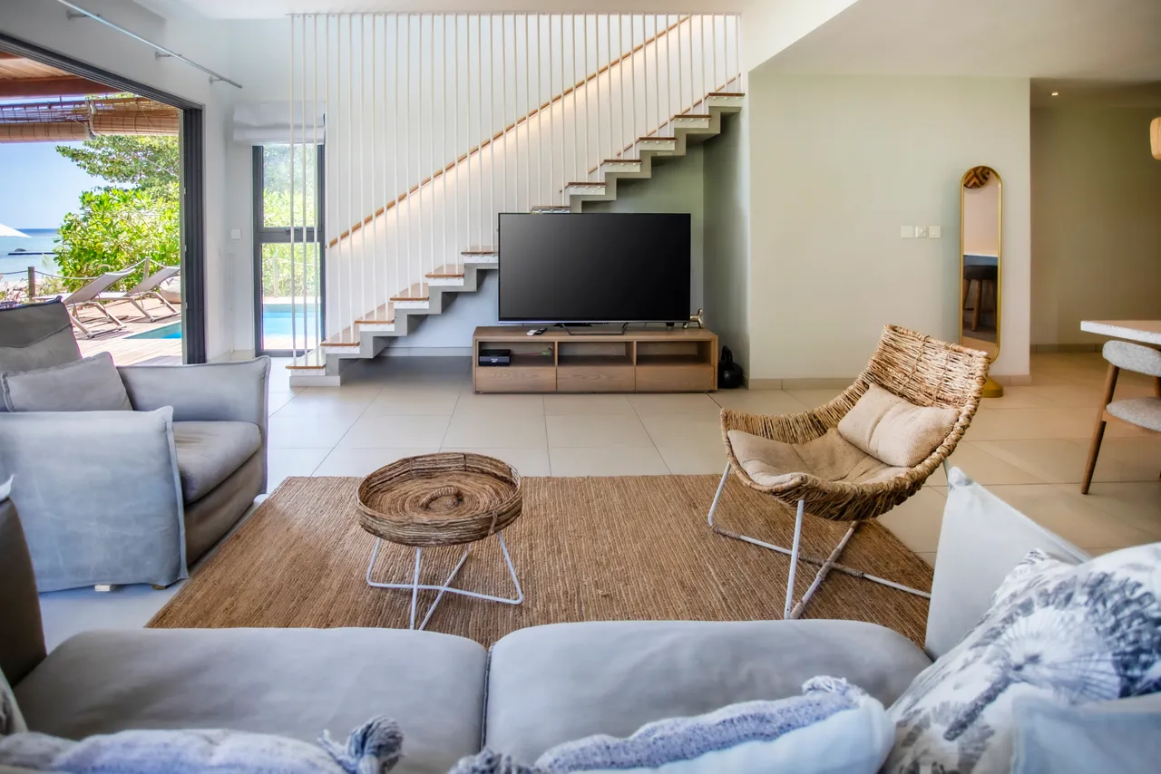 Espace de vie avec un canapé et une télévision, offrant une vue sur l'extérieur.