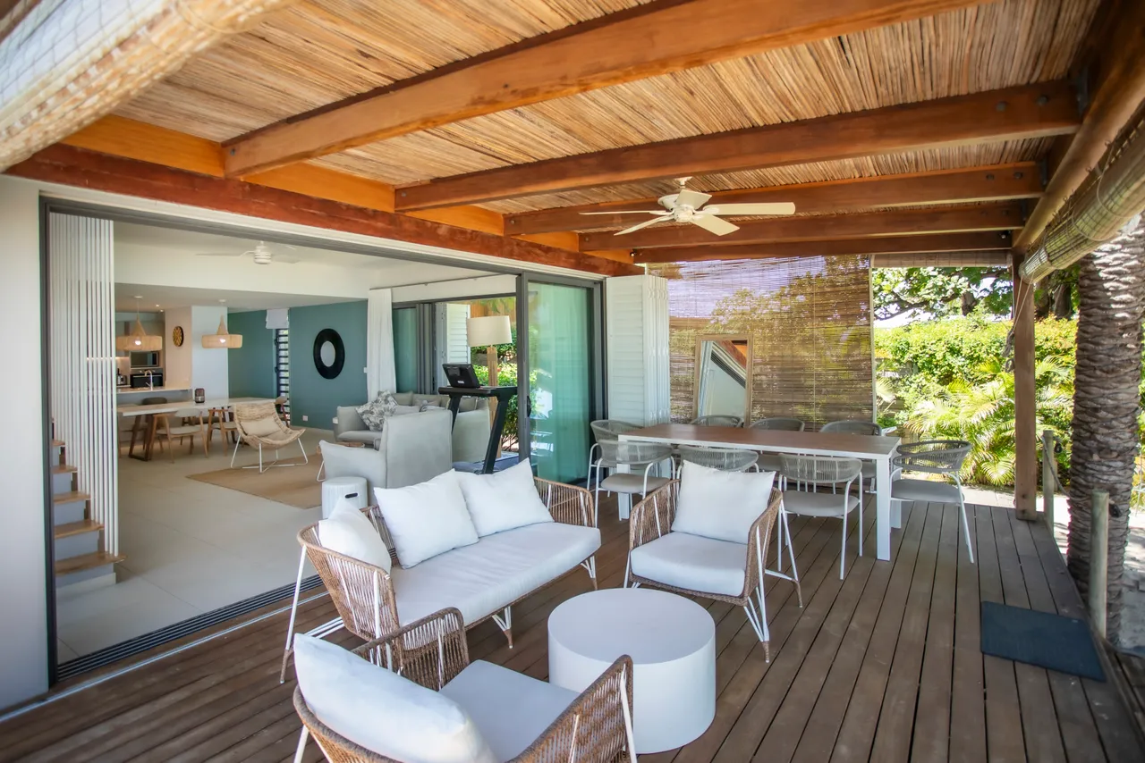 Bois clair et texture naturelle sur la terrasse ombragée. Espace accueillant avec mobilier en rotin et vue sur le jardin. Ventilation assurée grâce aux ouvertures latérales. Coin repas spacieux avec table et chaises confortables. Ambiance tranquille, idéal pour se détendre en extérieur.