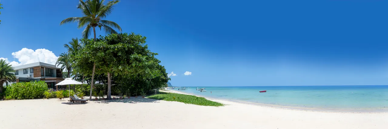 Plage de sable fin accessible directement depuis la villa. Végétation tropicale en arrière-plan.