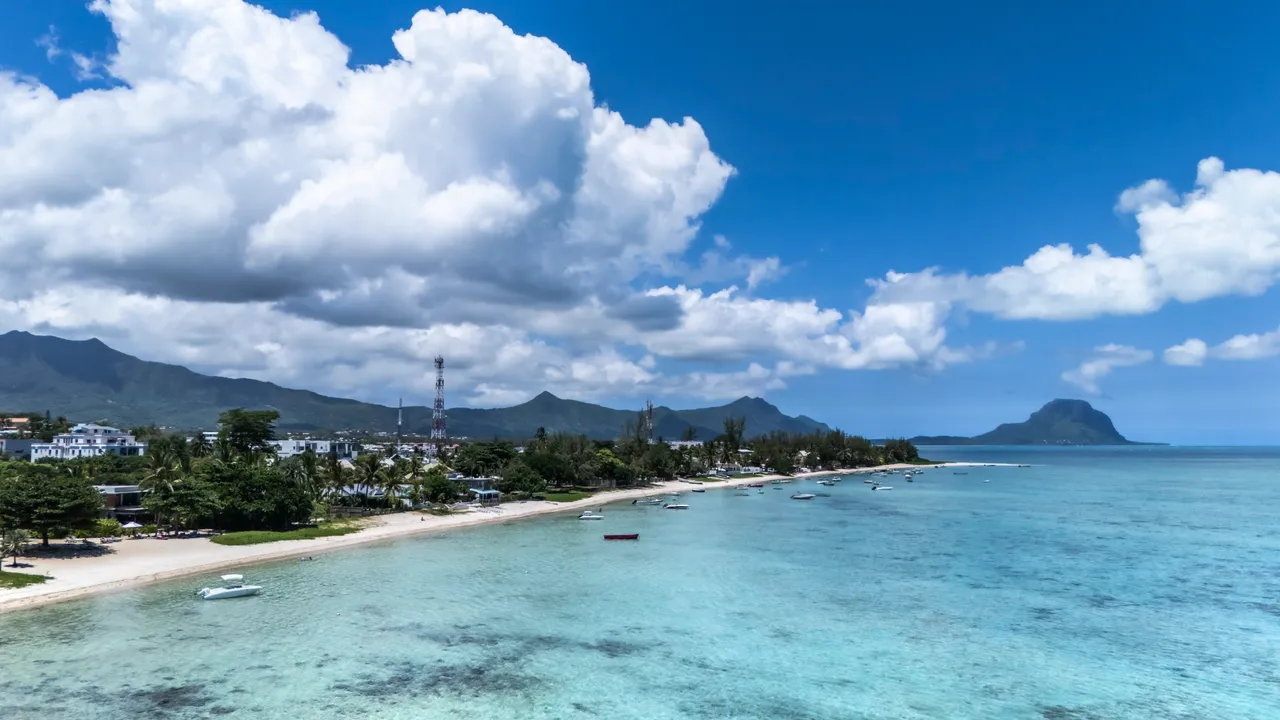 Vue dégagée sur la mer et la plage depuis la villa. Ciel clair avec quelques nuages. Accès direct à la plage depuis la propriété. Eaux calmes et transparentes.