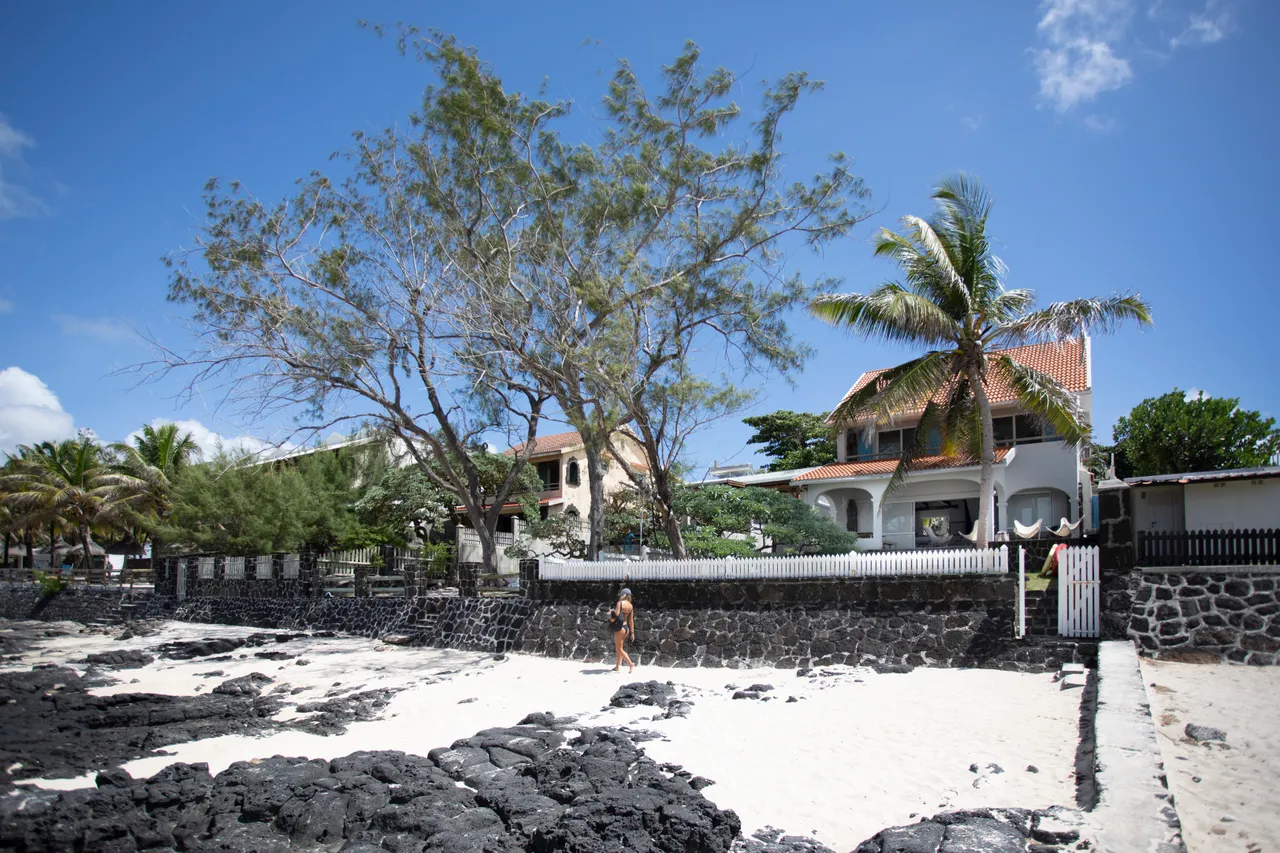 Espace extérieur avec accès à la plage, bordé de rochers et de végétation.