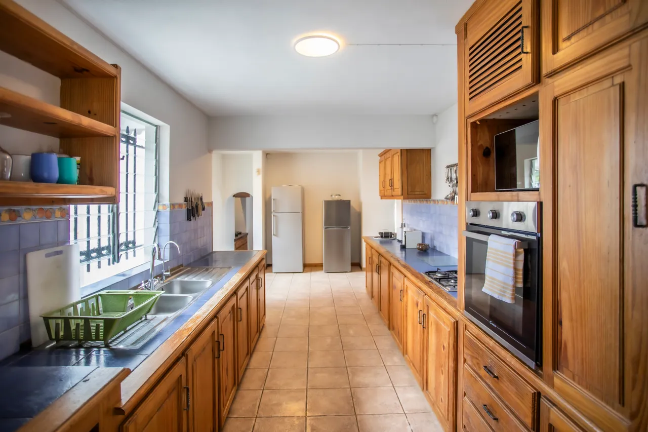 Bois chaleureux et carrelage clair, cuisine avec plans de travail spacieux. Rangements en bois et équipements électroménagers disponibles.