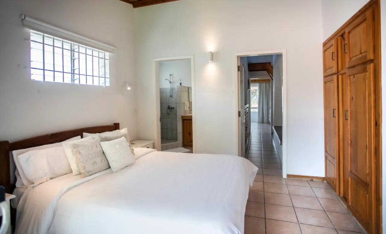 Chambre. Lit double avec éclairage naturel et placard en bois. Sol en carrelage clair.