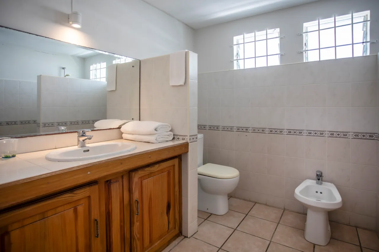 Salle de bains avec lavabo en bois et rangements intégrés. Éclairage naturel grâce aux fenêtres.