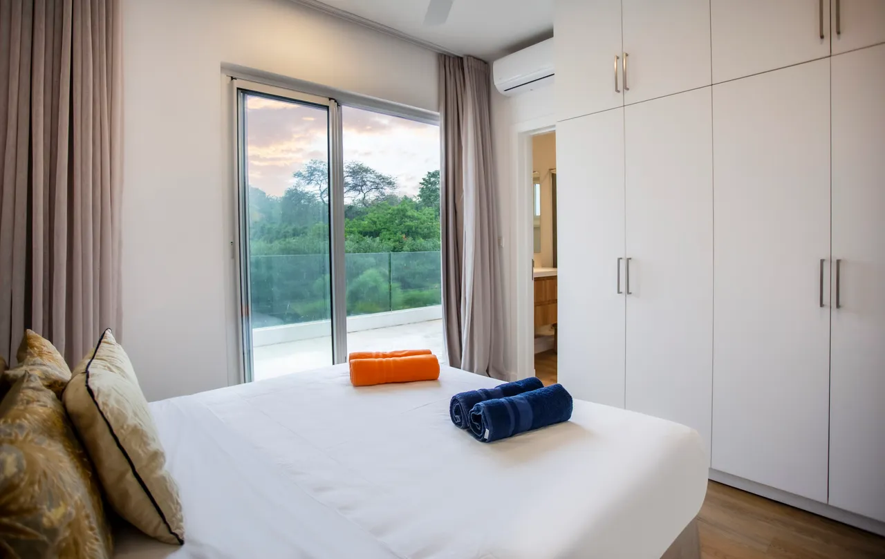 Chambre avec lit double et accès à un balcon.  
Rangements intégrés optimisant l'espace disponible pour les affaires.  
Linge de lit bien agencé, apportant une touche soignée.  
Fenêtre large offrant une vue dégagée sur l'extérieur.  
Éclairage naturel créant une atmosphère agréable dans la pièce.