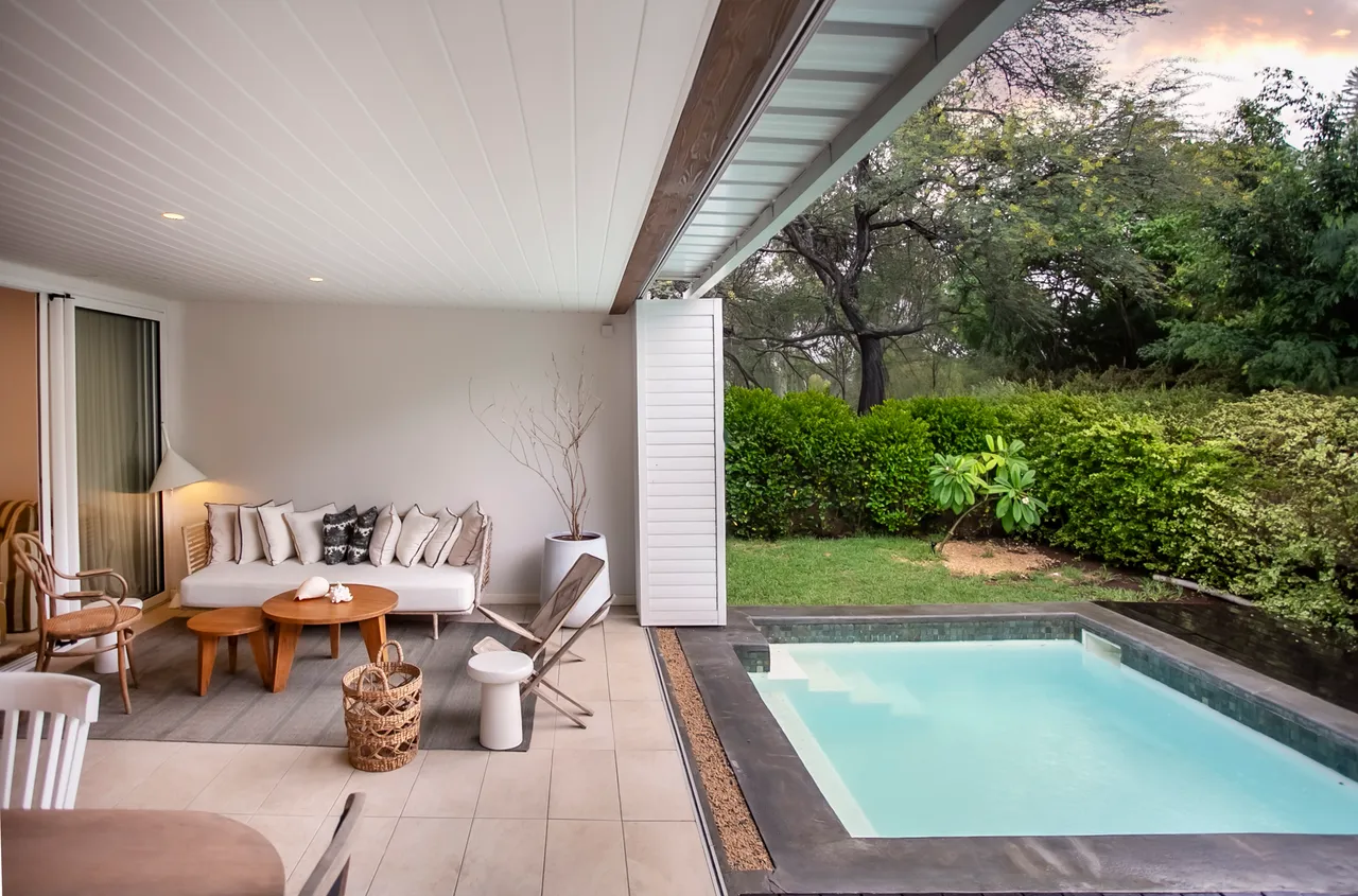 Espace extérieur avec piscine et coin salon pour la détente.  
Terrasse carrelée offrant un accès direct à la piscine.  
Végétation luxuriante entourant l'espace, ajoutant de l'intimité.  
Mobilier en bois créant un cadre convivial pour les repas.  
Éclairage doux sur la terrasse pour des soirées agréables.